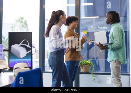 Eine vielfältige Gruppe junger Kollegen, die im Büro diskutieren, Papiere und Laptops halten Stockfoto