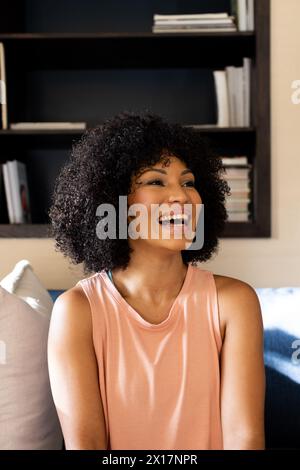 Birassische junge Frau lacht, sitzt zu Hause auf der Couch Stockfoto