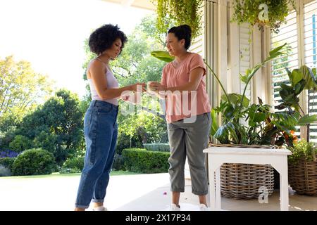 Birassische Mutter und Erwachsene Tochter trinken draußen Kaffee zu Hause Stockfoto