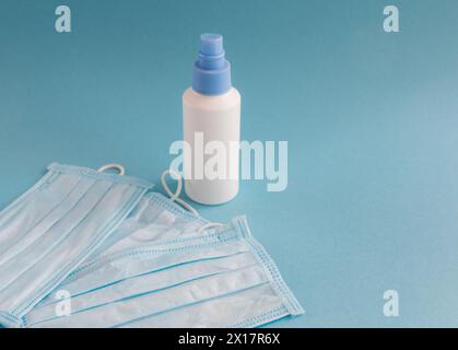 Desinfektionsspray und medizinische Maske für Hygiene auf dem blauen Hintergrund mit Platz für Text. Antibakteriell, gegen Verschmutzung oder Virusschutz. Covi Stockfoto