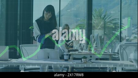 Eine Frau mit birassischer Herkunft arbeitet an einem Tablet-Computer in einem modernen Büro Stockfoto