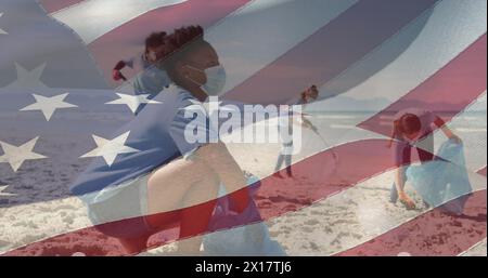 Ein Bild der amerikanischen Flagge gegen eine Gruppe verschiedener Freiwilliger, die den Strand reinigen Stockfoto