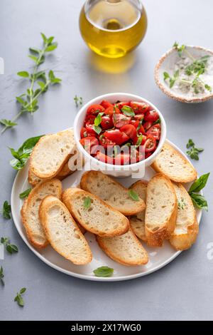 Zubereitung von Tomaten-Basilikum-Crostini oder Bruschetta mit geröstetem Baguette und Frischkäse Stockfoto