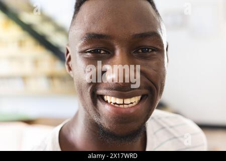 Ein junger Afroamerikaner mit einem hellen Lächeln, der zu Hause ein kariertes Hemd trägt Stockfoto