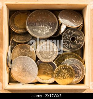 Alte Gold- und Silbermünzen in Holzkiste. Geld aus Frankreich, Polen, Italien, England, Österreich, Tschechische Republik, China, Kroatien, Dänemark, Niederlande. Stockfoto