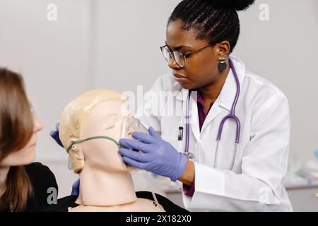 Eine Ärztin untersucht sorgfältig den Kopf einer Schaufensterpuppe, übt wahrscheinlich medizinische Verfahren oder demonstriert Techniken in einer klinischen Umgebung Stockfoto