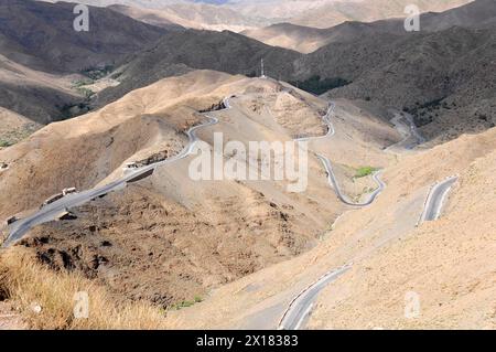 Blick auf den Tichka Pass, Col du Tichka, 2260 m, Eine kurvenreiche Straße schlängelt sich durch eine trockene Berglandschaft, südlicher Hochatlas, Marokko Stockfoto