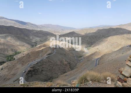 Blick auf den Tichka Pass, Col du Tichka, 2260 m, Eine Straße führt durch eine karge Berglandschaft mit karger Vegetation, südlicher Hoher Atlas, Marokko Stockfoto