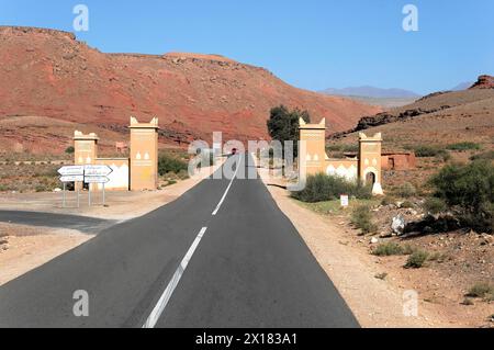 AIT Benhaddou, leere Autobahn in der Wüste, begrenzt von Bogengängen und Straßenschildern, südlicher hoher Atlas, Marokko Stockfoto