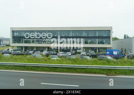 Waregem, Belgien - 22. Mai 2023: Ein modernes Bürogebäude mit großen Glasfenstern, die einen bewölkten Himmel reflektieren Stockfoto