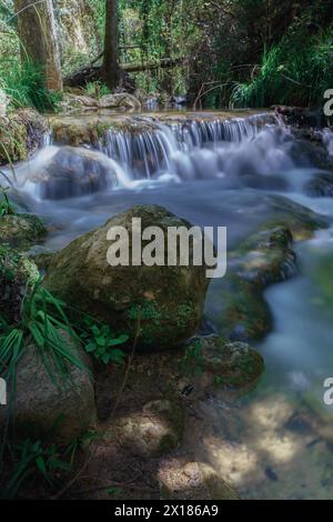 Langzeitfoto mit Seideneffekt von einem Wasserfall in einem Gebirgsbach mit üppiger Vegetation Stockfoto