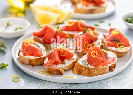 Geräucherte Lachs-Crostini mit Frischkäse, Dill und Zitronenschale auf einem Servierteller Stockfoto