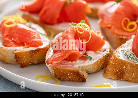 Geräucherte Lachs-Crostini mit Frischkäse, Dill und Zitronenschale auf einem Servierteller aus nächster Nähe Stockfoto