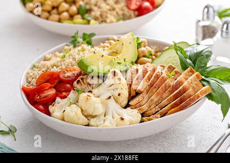 Gesunde Mittagsschale mit proteinreichem Essen, geschnittenem gegrilltem Hühnchen, Kichererbsen und Quinoa und frischem Gemüse Stockfoto