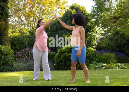 Birassische Mutter und Tochter sind im Garten zu Hause High-Five Stockfoto