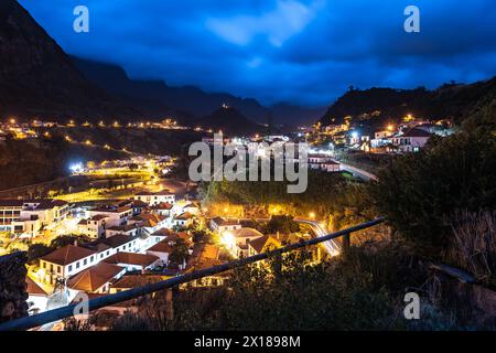 Beschreibung: Die nächtliche Atmosphäre, Straßenbeleuchtung und Autolampen des malerischen Dorfes an der Nordküste in einem grünen, bewachsenen valle Stockfoto