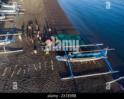 Die Fischer entladen ihren Fang am Morgen von ihrem Auslegerboot. Amed, Karangasem, Bali, Indonesien Stockfoto