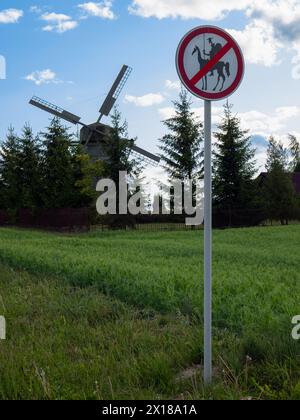 Dudutki, Weißrussland - 3. Juni 2023: Schild, das den Durchgang von Don Quijote und anderen wie ihm im Hintergrund einer Holzmühle verbietet. Lustiges Straßenschild Stockfoto