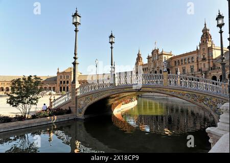 Plaza de Espana, Sevilla, Reflexion einer dekorativen Brücke und Straßenlaternen auf dem Wasser vor einer historischen Kulisse, Sevilla, Andalusien, Spanien Stockfoto