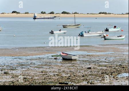 Guadalquivir, mehrere kleine Boote, die aufgrund der Ebbe auf trockenem Sand liegen, im Hintergrund ein größeres Schiff, Andalusien, Spanien Stockfoto