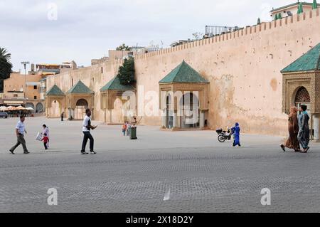 Meknes, Menschen, die über einen geräumigen Platz mit historischen Gebäuden im Hintergrund laufen, Nordmarokko, Marokko Stockfoto