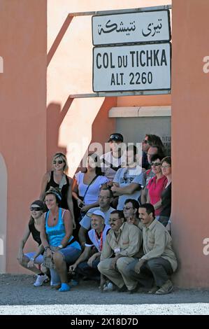 Am Tichka-Pass, Col du Tichka, 2260 m, macht Eine Gruppe lächelnder Menschen ein Foto unter dem Col du Tichka-Schild, südlicher hoher Atlas, Marokko Stockfoto