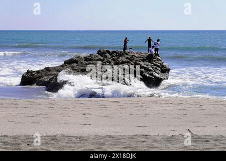 Las Penitas Strand in der Nähe von Poneloya, Leon, Pazifik, Nicaragua, Menschen auf einem Felsen am Strand mit brechenden Wellen, Mittelamerika, Mittelamerika Stockfoto