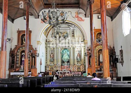 La Merced Kirche, erbaut um 1762, Leon, Nicaragua, Blick durch das Kirchenschiff zum Hauptaltar mit Gläubigen in den Bänken und einem Kronleuchter, Central Stockfoto