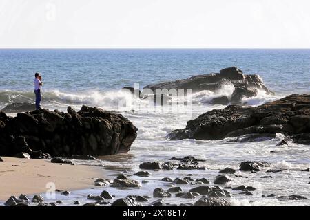 Strand in der Nähe von Poneloya, Las Penitas, Leon, Nicaragua, Eine Person steht auf Felsen am Meer und fotografiert die Wellen, Mittelamerika, Mittelamerika Stockfoto