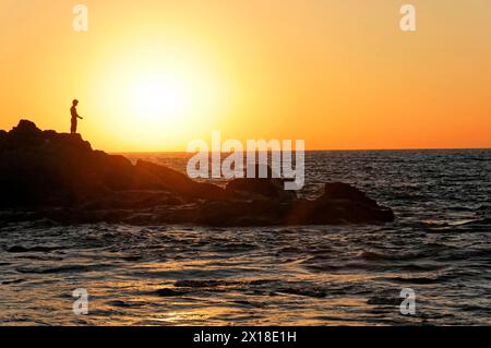 Strand in der Nähe von Poneloya, Las Penitas, Leon, Nicaragua, Silhouette einer Person auf Felsen am Meer bei Sonnenuntergang strahlt Frieden aus, Mittelamerika, Zentral Stockfoto