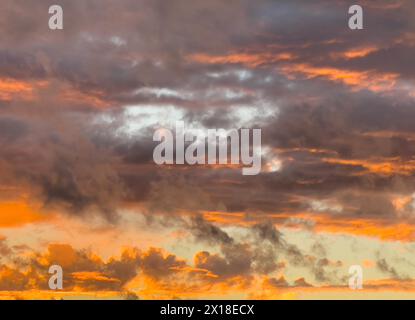 Verstreute Wolkendecke aus orange rötlichen und grauen Wolken Altocumulus vor bläulichem Abendhimmel in der Abenddämmerung, Deutschland Stockfoto