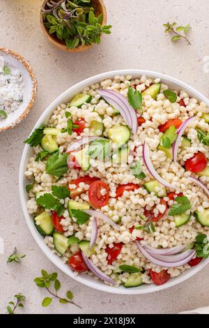 Perle Couscous Salat mit frischem Gemüse und Kräutern in einer Servierschale, gesunde Beilage Idee Stockfoto