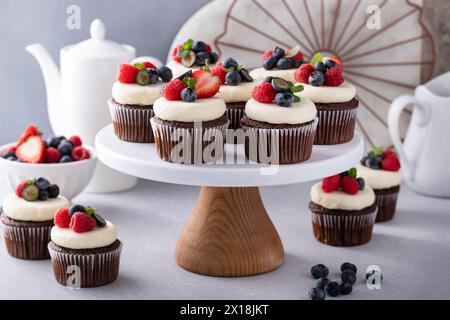 Schokoladen-Cupcakes mit Vanille-Buttercreme-Zuckerguss und frischen Beeren darauf Stockfoto
