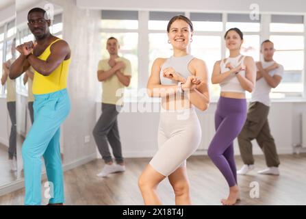 Junge weibliche Fitnesstrainerin, die die positive Zumba-Klasse anführt Stockfoto