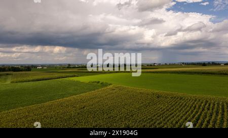 Dramatische Sturmwolken ziehen sich über ein Flickenteppich von Ackerland und unterstreichen das dynamische Zusammenspiel von Wetter und Landwirtschaft. Stockfoto