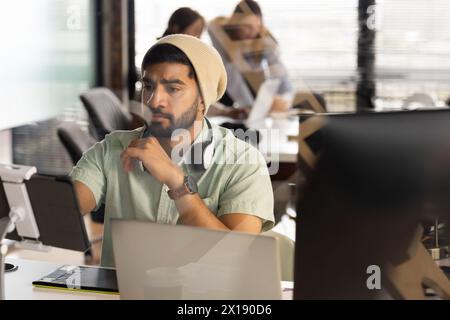 Asiatischer männlicher junger Profi, der in einem modernen Geschäftsbüro tief nachdenklich auf den Tablet-Bildschirm blickt Stockfoto