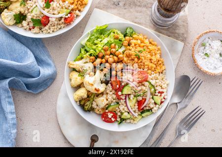 Vegane Mittagsschale mit geröstetem Gemüse, frischem Salat, gekochten Linsen, Couscous-Salat und knusprigen gerösteten Kichererbsen Stockfoto