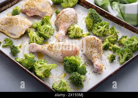 Hähnchenkeulen und Schenkel mit Brokkoli-Blechpfanne Abendessen oder Mittagessen mit Knoblauch und Kräutern roh zum Backen Stockfoto
