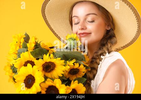 Junge Frau mit schönen Sonnenblumen auf gelbem Hintergrund, Nahaufnahme Stockfoto