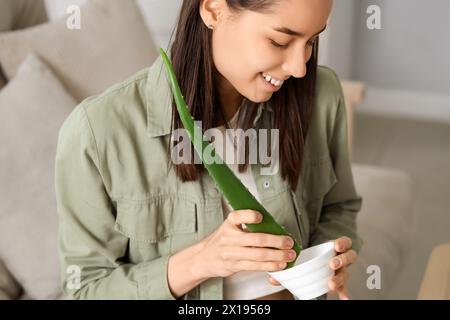 Schöne junge Frau, die Aloe Vera Gel im Wohnzimmer herstellt Stockfoto