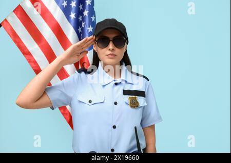 Grüßende Polizistin und Flagge der USA auf blauem Hintergrund Stockfoto