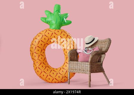 Aufblasbarer Ring in Form von Ananas und Strohstuhl mit Tasche und Hut auf rosa Hintergrund Stockfoto