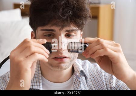 Ein junger Mann mit Verbrennungsgesicht und Stecker zu Hause, Nahaufnahme Stockfoto