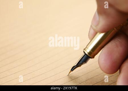 Die Hand eines Mannes, der mit einem Füllfederhalter auf Papier schreibt Stockfoto