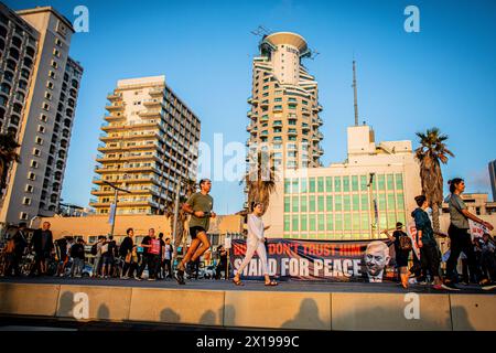Tel Aviv, Israel. April 2024. Ein Mann läuft an einem Banner vorbei, das US-Präsident Joe Biden aufruft, den israelischen Premierminister Benjamin Netanjahu während einer Demonstration daran zu hindern, den Iran anzugreifen. Israel hat nach einem beispiellosen Drohnen- und Raketenangriff am Wochenende, der die regionalen Spannungen, die durch den Krieg in Gaza geschürt wurden, verschärft hat, gelobt, vom Iran einen "Preis" abzugeben. (Foto von Eyal Warshavsky/ SOPA Images/SIPA USA) Credit: SIPA USA/Alamy Live News Stockfoto