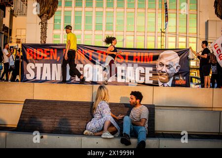 Tel Aviv, Israel. April 2024. Eine Frau schaut auf ein Banner zurück, das US-Präsident Joe Biden aufruft, den israelischen Premierminister Benjamin Netanjahu während einer Demonstration daran zu hindern, den Iran anzugreifen. Israel hat nach einem beispiellosen Drohnen- und Raketenangriff am Wochenende, der die regionalen Spannungen, die durch den Krieg in Gaza geschürt wurden, verschärft hat, gelobt, vom Iran einen "Preis" abzugeben. Quelle: SOPA Images Limited/Alamy Live News Stockfoto