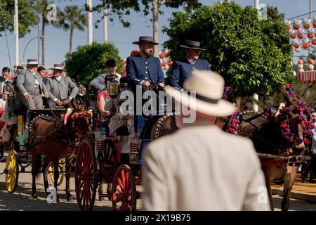 Männer, die auf Pferden reiten, werden während einer Parade auf der Messe Kutschen ziehen sehen. Die Aprilmesse ist eines der internationalen und beliebtesten Festivals in Sevilla. 1847 als Viehmesse gegründet, übernahm der festliche Aspekt der Veranstaltung im Laufe der Zeit den kommerziellen Teil, bis sie zu einem wichtigen Ereignis für die Sevillianer wurde. Eine Woche lang wurden mehr als tausend Stände auf dem Messegelände zum zweiten Zuhause der Einwohner dieser Stadt, ein Ort, an dem sie sich teilen und Spaß in Gesellschaft haben können bis in die frühen Morgenstunden. Während des Festivals werden die Leute in typischen Anda gekleidet Stockfoto