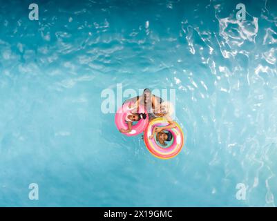 Vielfältige Familie, die zu Hause Poolzeit genießen, auf bunten Ringen schwimmen, Kopierraum Stockfoto