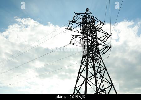 Telefonmast und Kabel gegen blauen Himmel mit Wolken Stockfoto