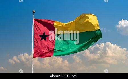 Die Fahne von Guinea-Bissau, flattert im Wind, isoliert, gegen den blauen Himmel Stockfoto